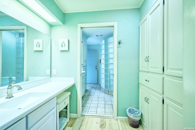 bathroom with visible vents, ornamental molding, a sink, wood finished floors, and baseboards