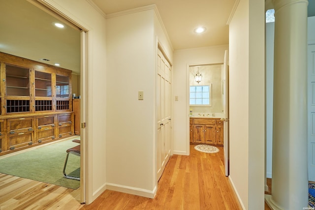 corridor with light wood-style floors, baseboards, and crown molding