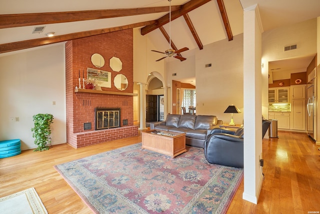 living room with light wood finished floors, a brick fireplace, and visible vents