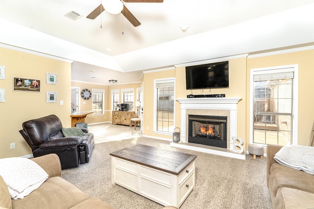 living area with a fireplace, visible vents, crown molding, and light colored carpet