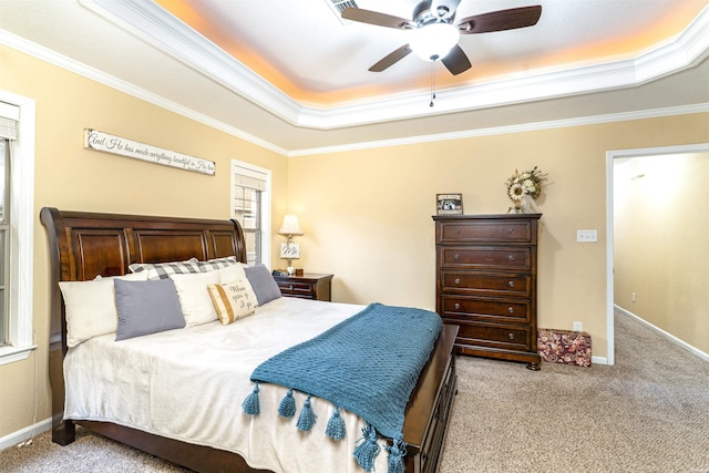 carpeted bedroom with a ceiling fan, baseboards, a tray ceiling, and crown molding