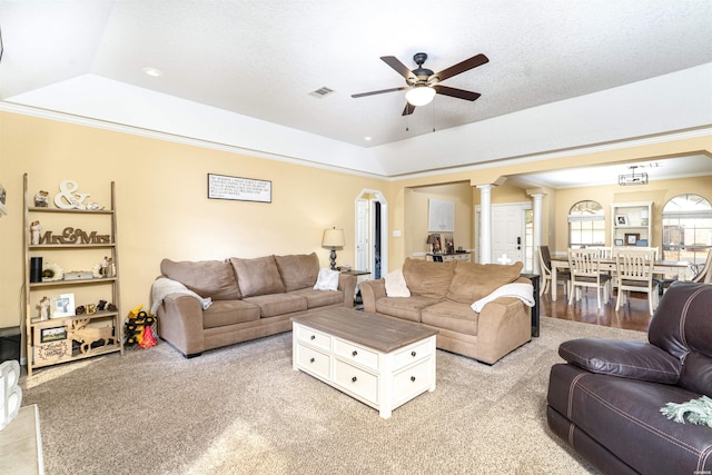 living area with decorative columns, ornamental molding, a raised ceiling, and visible vents