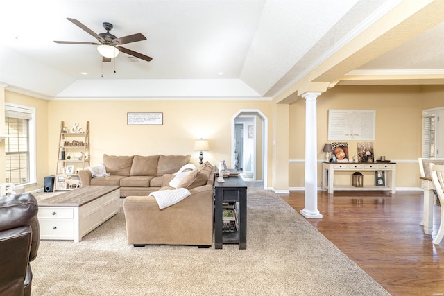 living area with crown molding, a raised ceiling, decorative columns, and wood finished floors