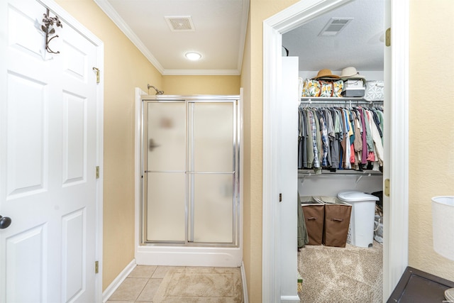 full bath featuring a stall shower, a walk in closet, visible vents, and tile patterned floors