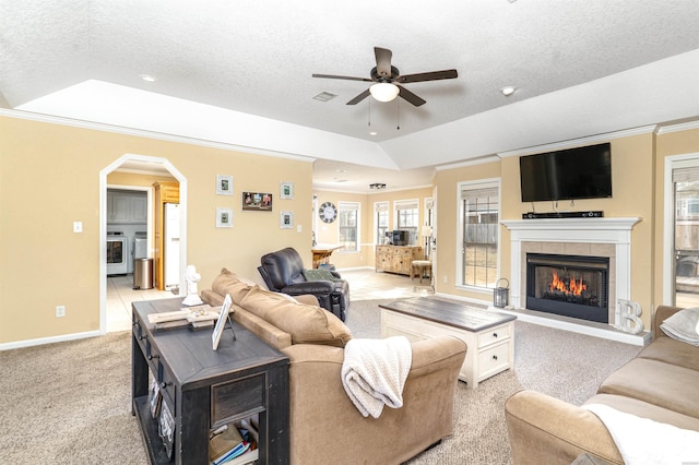 living room with light carpet, arched walkways, a raised ceiling, and crown molding