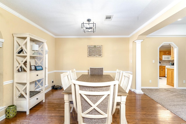 dining room with arched walkways, wood-type flooring, visible vents, and ornate columns