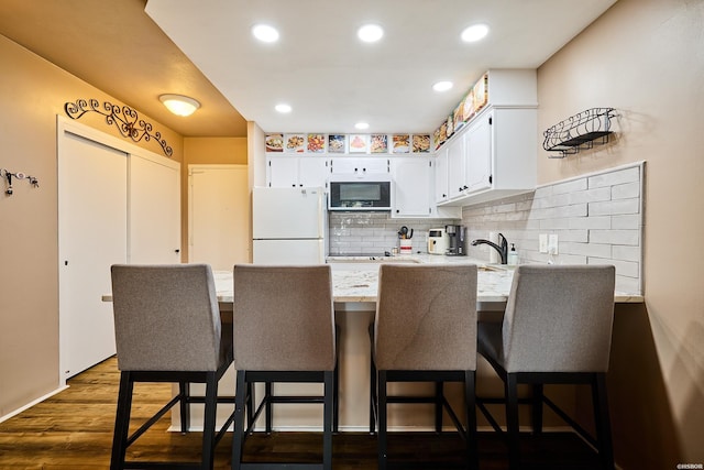 740 Weston Rd Unit A-508, Hot Springs, AR 71913 - kitchen featuring a peninsula, white appliances, dark wood finished floors, backsplash, and white cabinets