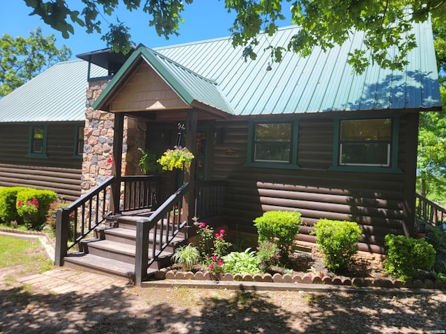 log cabin featuring metal roof and a chimney