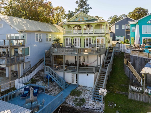 rear view of house with stairs, french doors, fence, and a balcony