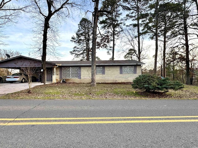 ranch-style house featuring a carport, brick siding, and driveway