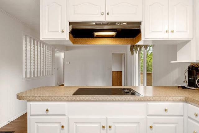 kitchen with white cabinets, ornamental molding, black electric cooktop, light countertops, and under cabinet range hood