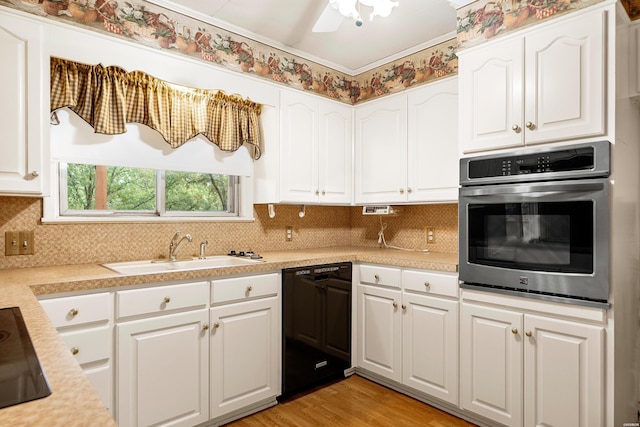 kitchen with a sink, white cabinetry, light countertops, decorative backsplash, and black appliances