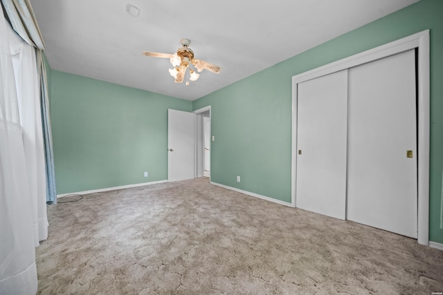 unfurnished bedroom featuring ceiling fan, a closet, baseboards, and light colored carpet