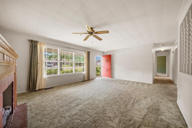 spare room with carpet, a brick fireplace, visible vents, and ceiling fan