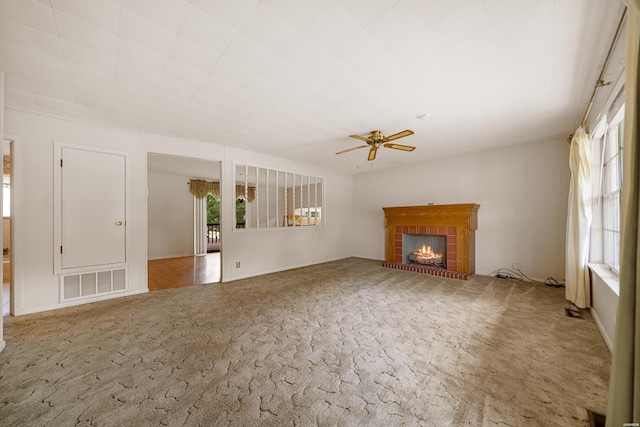 unfurnished living room featuring carpet, visible vents, a fireplace, and ceiling fan