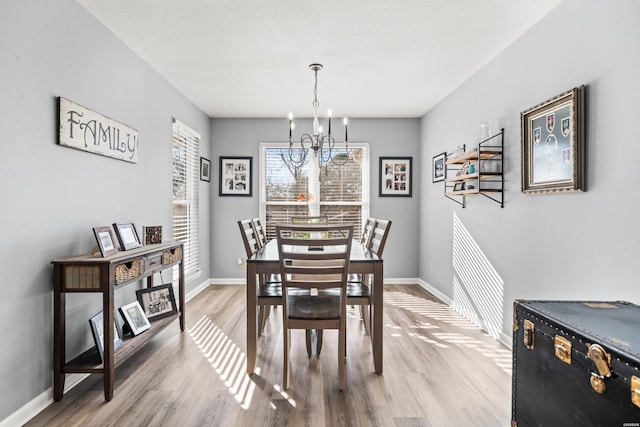 dining area with a notable chandelier, baseboards, and wood finished floors