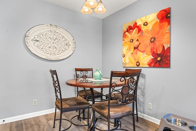 dining room featuring an inviting chandelier, wood finished floors, and baseboards