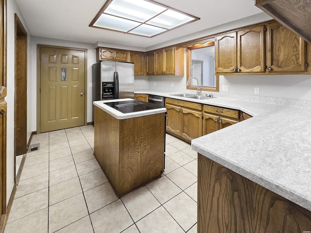 kitchen featuring light tile patterned flooring, stainless steel appliances, a sink, light countertops, and brown cabinetry