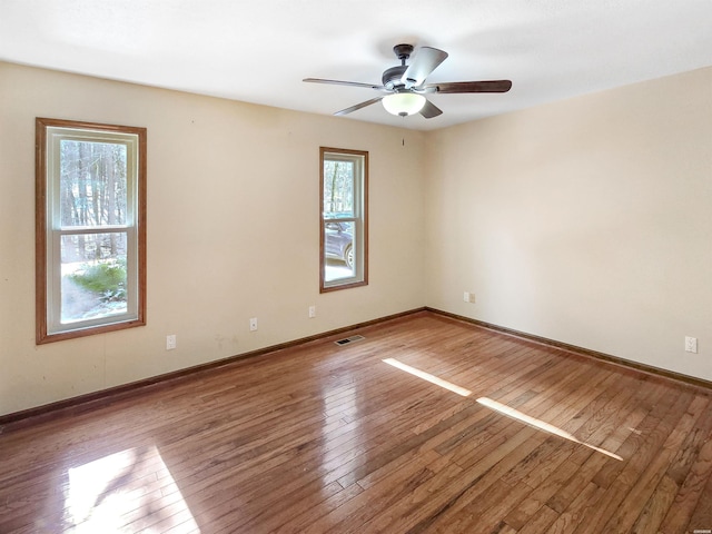 unfurnished room with baseboards, wood finished floors, visible vents, and a ceiling fan