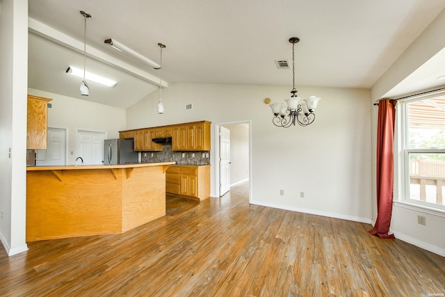 261 Pin Oak Dr, Bismarck, AR 71929 - kitchen with freestanding refrigerator, a kitchen breakfast bar, backsplash, wood finished floors, and a peninsula
