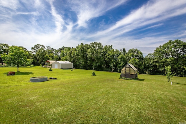261 Pin Oak Dr, Bismarck, AR 71929 - view of green lawn featuring an exterior structure, an outdoor structure, a fire pit, and view of wooded area