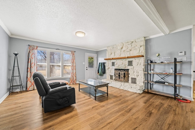 living area featuring ornamental molding, wood finished floors, and a stone fireplace