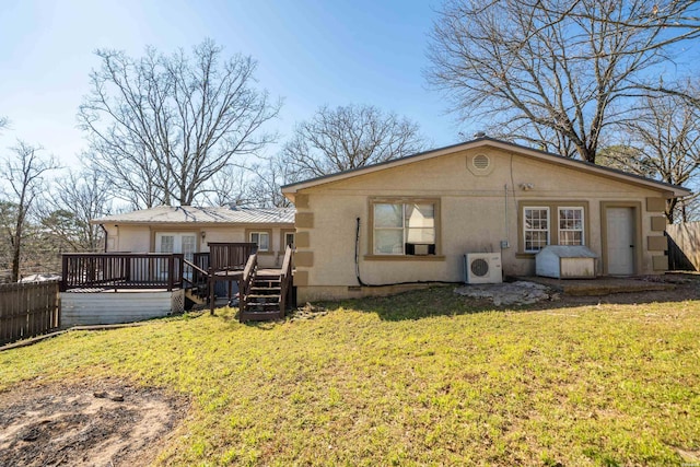 rear view of property featuring ac unit, fence, a wooden deck, and a lawn