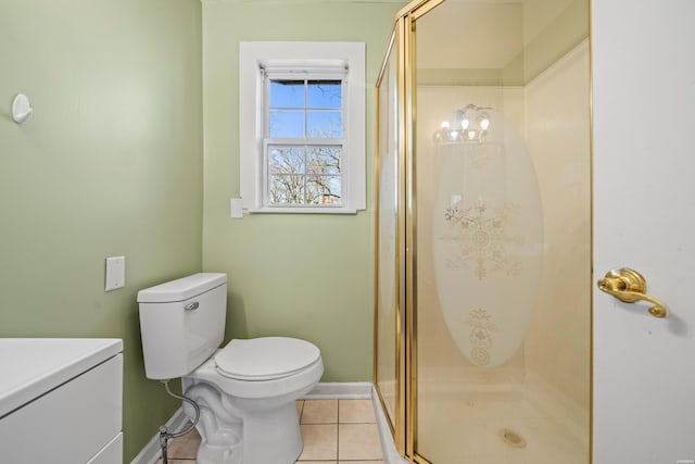 bathroom featuring a stall shower, tile patterned flooring, baseboards, and toilet