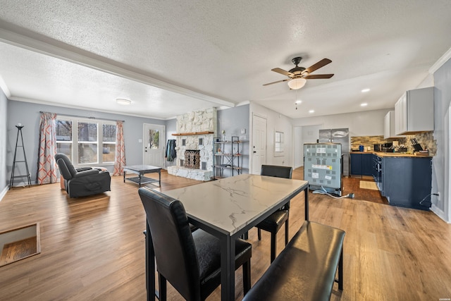 dining space featuring a fireplace, crown molding, and light wood finished floors