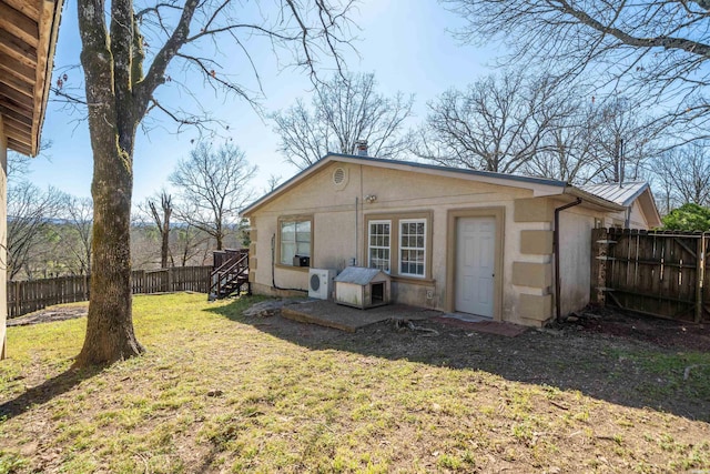 back of house with a fenced backyard, stairway, metal roof, a yard, and stucco siding