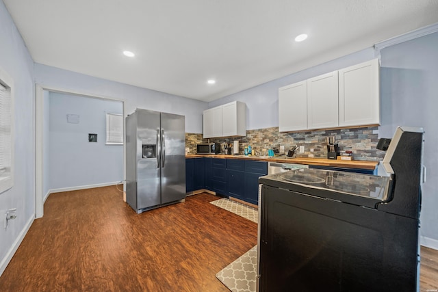 kitchen with dark wood-type flooring, white cabinetry, baseboards, appliances with stainless steel finishes, and tasteful backsplash