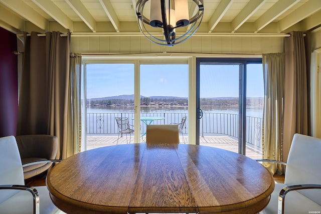 dining area with beam ceiling, a water view, and a notable chandelier