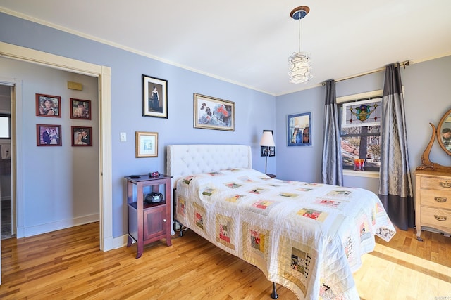 bedroom featuring light wood finished floors, baseboards, and crown molding