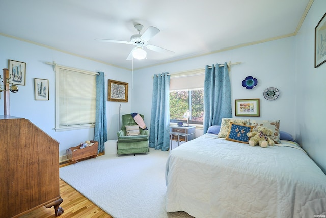 bedroom with light wood-style flooring, a ceiling fan, and crown molding