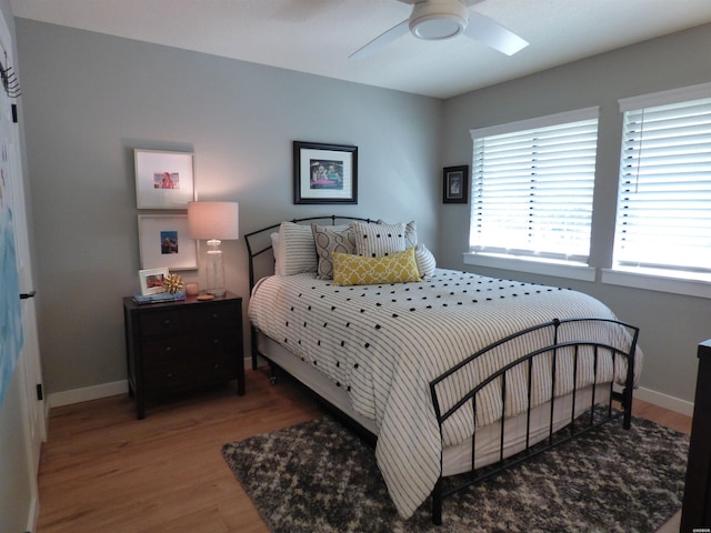 bedroom with a ceiling fan, baseboards, and wood finished floors