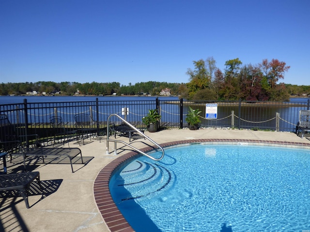 view of swimming pool with a water view and fence