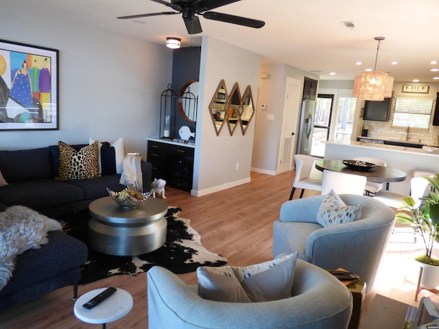 living room with recessed lighting, a ceiling fan, visible vents, baseboards, and light wood finished floors