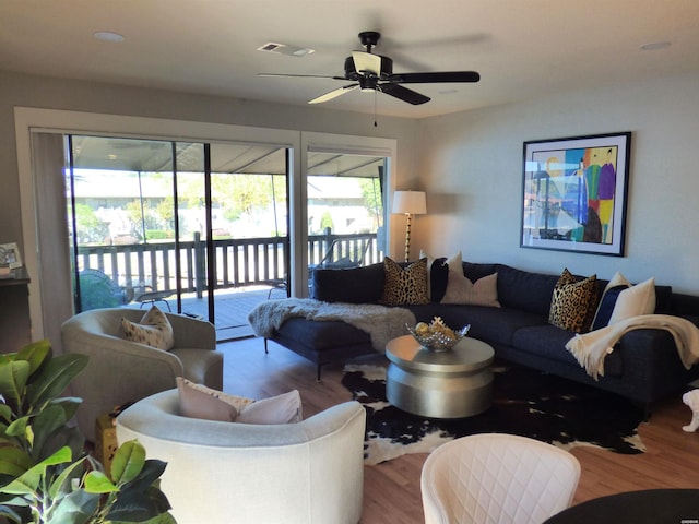 living area with light wood-style floors, visible vents, and ceiling fan