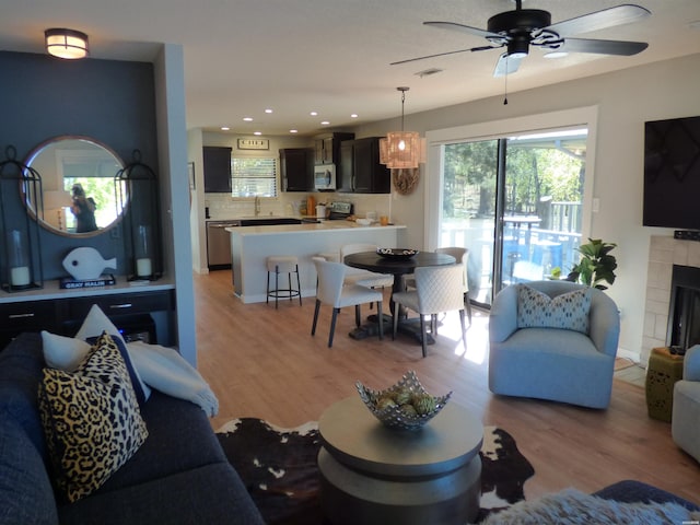 living room featuring a tile fireplace, visible vents, light wood-style flooring, and recessed lighting