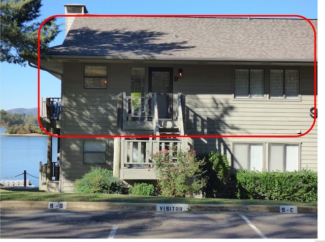 view of front facade with uncovered parking and roof with shingles