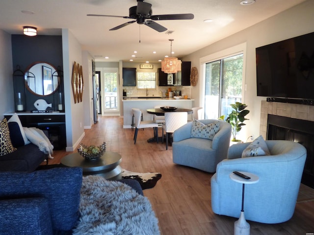 living room featuring recessed lighting, ceiling fan, wood finished floors, a tile fireplace, and baseboards