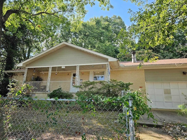 view of front of house featuring an attached garage, covered porch, fence, and brick siding