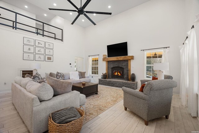 living area with a towering ceiling, light wood-style floors, a fireplace, and recessed lighting