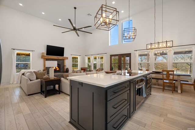 kitchen featuring light countertops, french doors, appliances with stainless steel finishes, dark cabinetry, and an island with sink