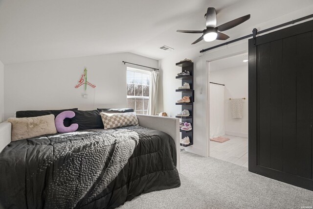 bedroom featuring lofted ceiling, ceiling fan, a barn door, light carpet, and visible vents