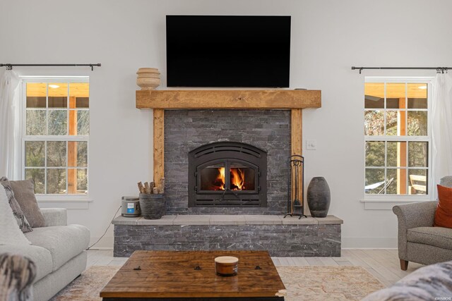 living room with light wood-style floors, a wealth of natural light, a glass covered fireplace, and baseboards