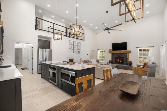 dining area with a fireplace, recessed lighting, light wood-style flooring, a high ceiling, and a ceiling fan