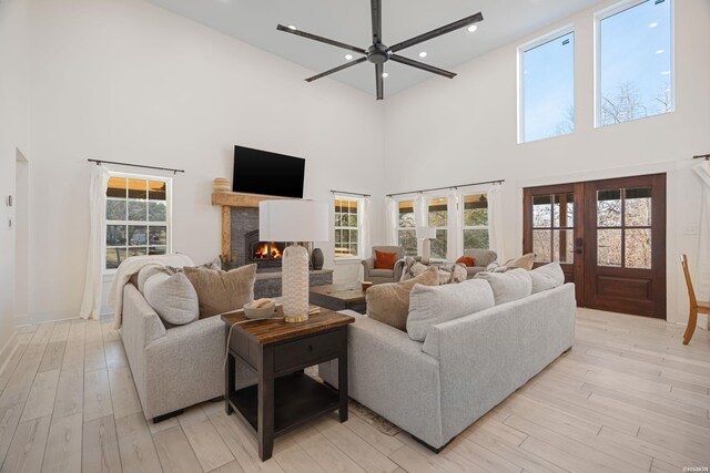 living room with french doors, recessed lighting, a ceiling fan, light wood-type flooring, and a lit fireplace