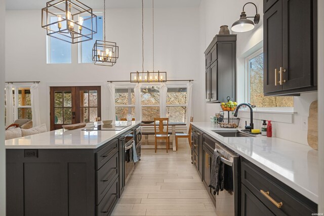 kitchen with a kitchen island, hanging light fixtures, an inviting chandelier, stainless steel dishwasher, and a sink