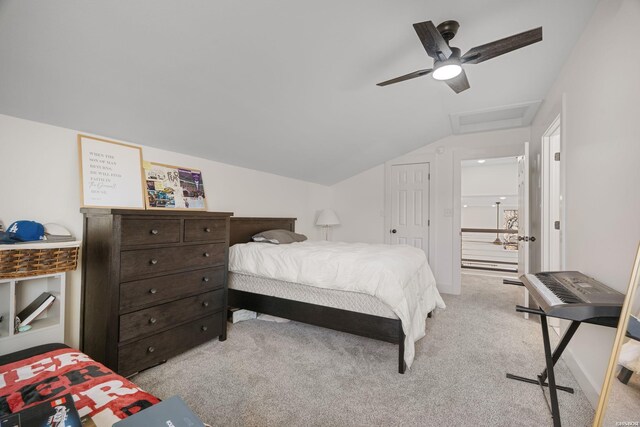 bedroom featuring light carpet, attic access, vaulted ceiling, and a ceiling fan